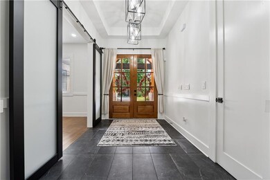 Foyer entrance featuring a barn door, french doors, a raised ceiling, and dark tile patterned flooring