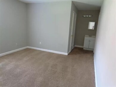 Spare room with light carpet, baseboards, and a si