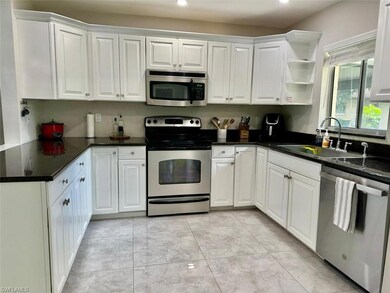 Fully renovated kitchen with granite countertops, crisp white cabinetry, stainless steel appliances, and designer pendant lights for a clean, modern finish.