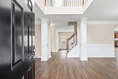 Foyer with dark wood-style floors, stairway, and ornamental molding