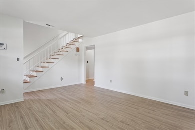 Unfurnished living room featuring light wood finished floors and stairs