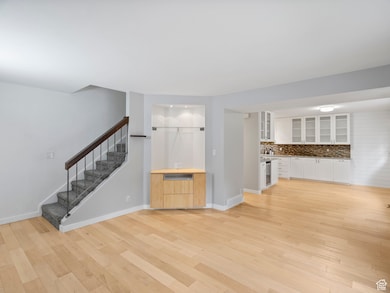 Unfurnished living room featuring light wood-style floors, stairs, and beverage cooler