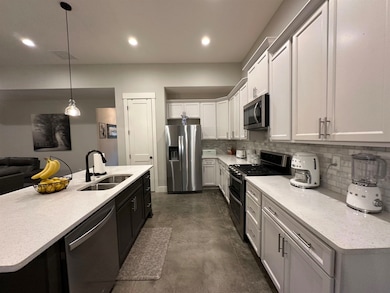 Kitchen featuring appliances with stainless steel finishes, a sink, tasteful backsplash, a kitchen island with sink, and recessed lighting