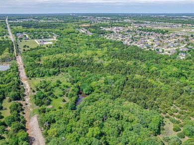 Aerial view of property and surrounding area with a heavily wooded area