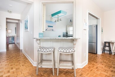 Kitchen featuring freestanding refrigerator, a breakfast bar area, white cabinets, beverage cooler, and light stone countertops