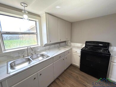 Kitchen with white cabinetry, a sink, light counte