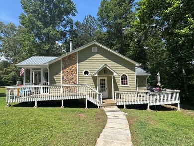 View of front facade with a front lawn, a deck, and stone siding