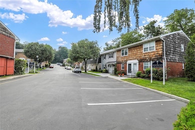 View of asphalt road featuring a residential view, curbs, and street lights