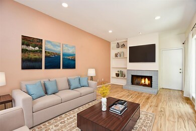 Spacious living room featuring a woodburning fireplace and newly installed laminate floors. (virtually staged)