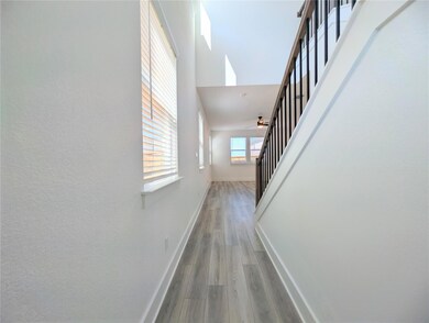 Hall with stairs, light wood-style flooring, and a high ceiling