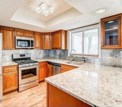 Kitchen featuring brown cabinetry, appliances with stainless steel finishes, and a textured ceiling