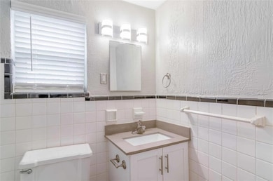 Bathroom with vanity, toilet, and tile walls