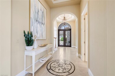 Tiled foyer featuring a tray ceiling and a chandel