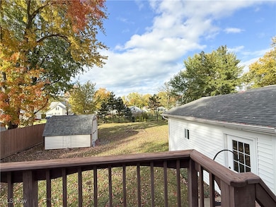 View of yard with a shed, view of wooded area, and a balcony