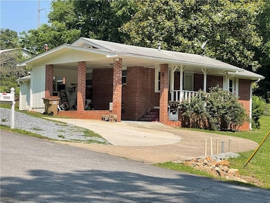 View of front facade featuring driveway, brick siding, and a porch