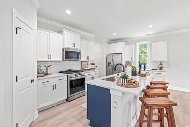 Kitchen with stainless steel appliances, a sink, light wood-style flooring, a kitchen island with sink, and light countertops