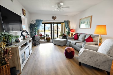 Living room featuring light wood finished floors, a water view, and a ceiling fan