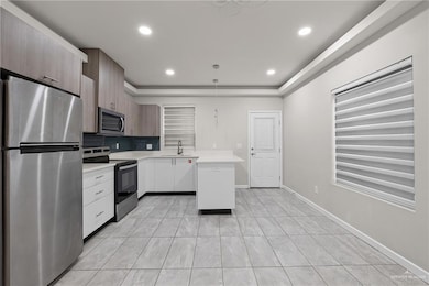Kitchen with appliances with stainless steel finishes, light countertops, modern cabinets, decorative backsplash, and a sink