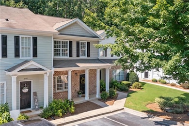 View of property featuring brick siding, uncovered parking, a front lawn, and roof with shingles