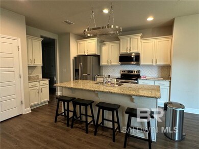 Kitchen featuring appliances with stainless steel finishes, white cabinets, a center island with sink, sink, and dark hardwood / wood-style flooring