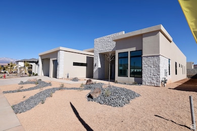 Rear view of house with a garage, stone siding, driveway, and stucco siding