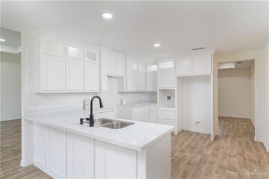 Kitchen with a peninsula, light wood-style flooring, glass insert cabinets, white cabinetry, and recessed lighting
