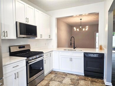 Kitchen featuring appliances with stainless steel finishes, light countertops, white cabinets, and a textured ceiling
