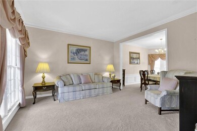 Carpeted living area featuring crown molding, a wa