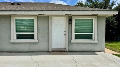Doorway to property with a shingled roof, a patio, and stucco siding