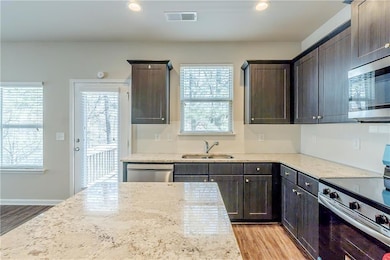 Kitchen featuring a sink, visible vents, stainless steel appliances, and dark brown cabinets