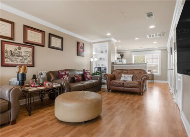 Living area with light wood finished floors, crown