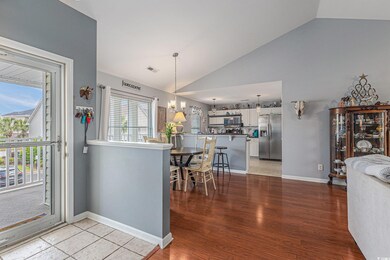 Dining area/Kitchen featuring stainless steel fridge, vaulted ceiling, white cabinetry, light wood-style floors, and pendant lighting