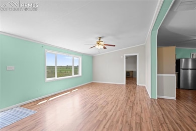 Unfurnished living room with crown molding, wood finished floors, and a ceiling fan