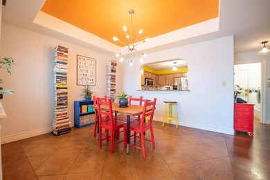 Tiled dining space featuring a tray ceiling, a ch