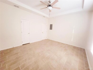 Empty room with a raised ceiling, a ceiling fan, and electric panel