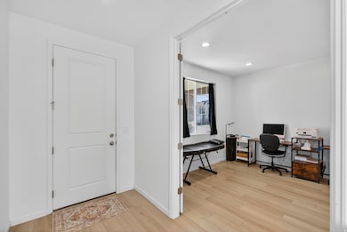 Office with light wood-style floors and recessed lighting