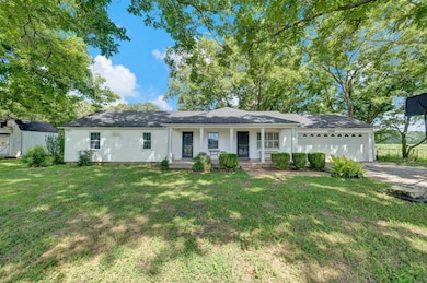 Ranch-style house with a porch, a front yard, an attached garage, and driveway