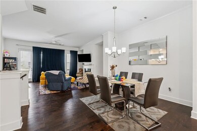 Dining area featuring a chandelier, hardwood / wood-style floors, ornamental molding, a fireplace, and ceiling fan