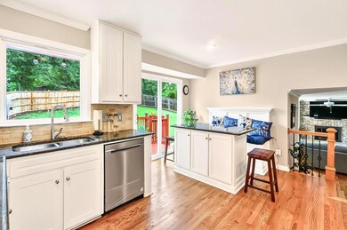 Kitchen featuring stainless steel dishwasher, a sink, a breakfast bar, light wood floors, and crown molding