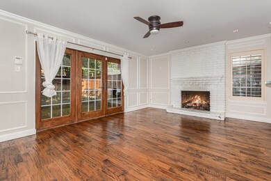 Unfurnished living room featuring a decorative wall, healthy amount of natural light, crown molding, dark wood-type flooring, and a ceiling fan