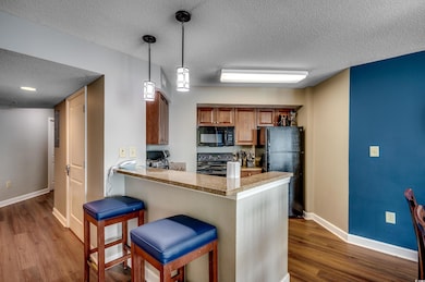 Kitchen with black appliances, a textured ceiling,