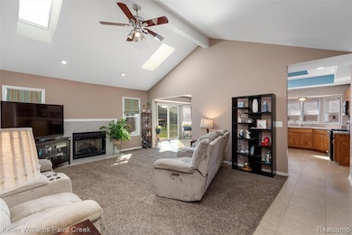 Living area featuring a skylight, recessed lighting, a tiled fireplace, high vaulted ceiling, and plenty of natural light