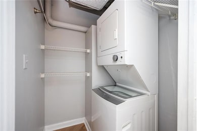 Private in suite Laundry room featuring estacked washer and dryer, wood finished floors, and baseboards