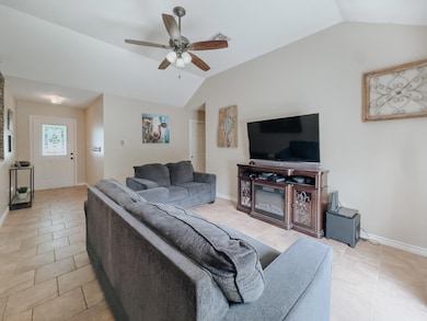 Tiled living room featuring ceiling fan and vaulted ceiling