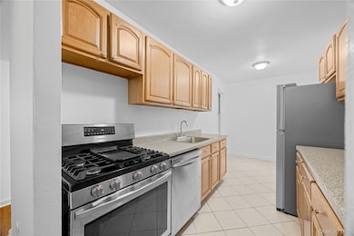 Kitchen with appliances with stainless steel finishes, light tile patterned floors, and light brown cabinetry