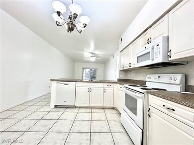 Kitchen featuring white appliances, a peninsula, d