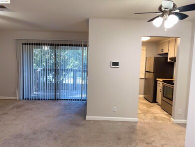 Kitchen featuring light carpet, stainless steel range with electric stovetop, ceiling fan, and light countertops