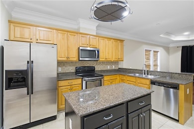 Kitchen featuring ornamental molding, stainless steel appliances, dark stone counters, tasteful backsplash, and a peninsula