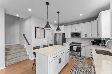 The spacious kitchen is designed for both style and functionality, featuring quartz countertops, stainless steel GE appliances, and a beautiful tile backsplash.