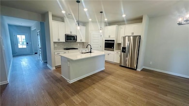 Kitchen featuring appliances with stainless steel finishes, a sink, backsplash, white cabinetry, and recessed lighting